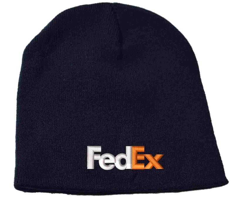 Pode incluir: Um gorro de malha azul marinho com um logotipo FedEx bordado em branco e laranja.