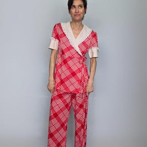 A woman wearing a red and white checkered outfit stands against a plain background.