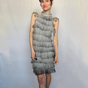 a woman in a gray dress standing in front of a white backdrop