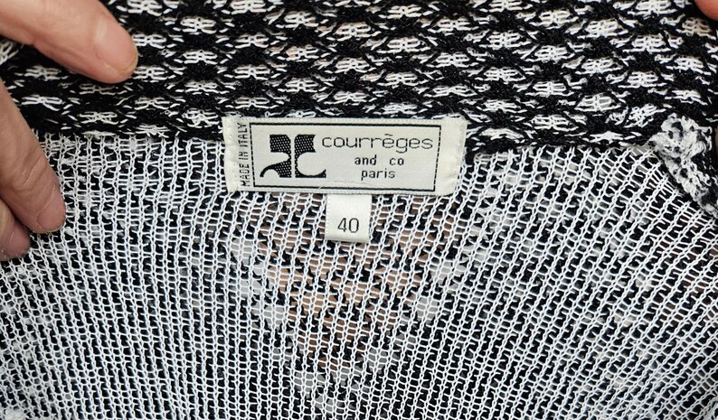 May include: Black and white knit sweater with a black label that reads "Courr&egrave;ges and co paris" and "Made in Italy". The label also has a size tag that reads "40".