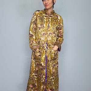 May include: A white ceramic mug with a black handle and the text "But First, Coffee" in a bold, black font. The mug is set against a blurred background, suggesting a cosy setting.