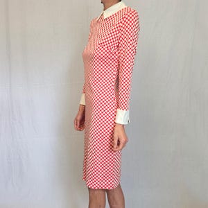 May include: A vintage dress with a red and white polka dot design. The dress has long sleeves, a white collar, and white cuffs. The dress is knee-length.