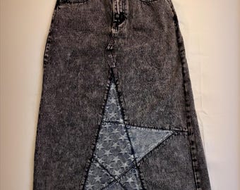 Könnte beinhalten: Langer Jeansrock mit Säurewaschung, hoher Taille und geteilter Front. Der Rock hat ein großes sternförmiges Panel aus hellerem Denim mit Sternmuster. Der Rock hat ein klassisches Fünf-Taschen-Design.