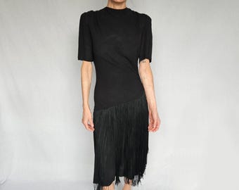 May include: A black dress with a short sleeve and a fringe hem.