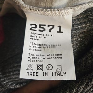 May include: A white label with the number "2571" printed in black, along with fabric composition details: 100% silk, 95% viscose, and 5% elastane. The label also includes care symbols and the text "MADE IN ITALY."