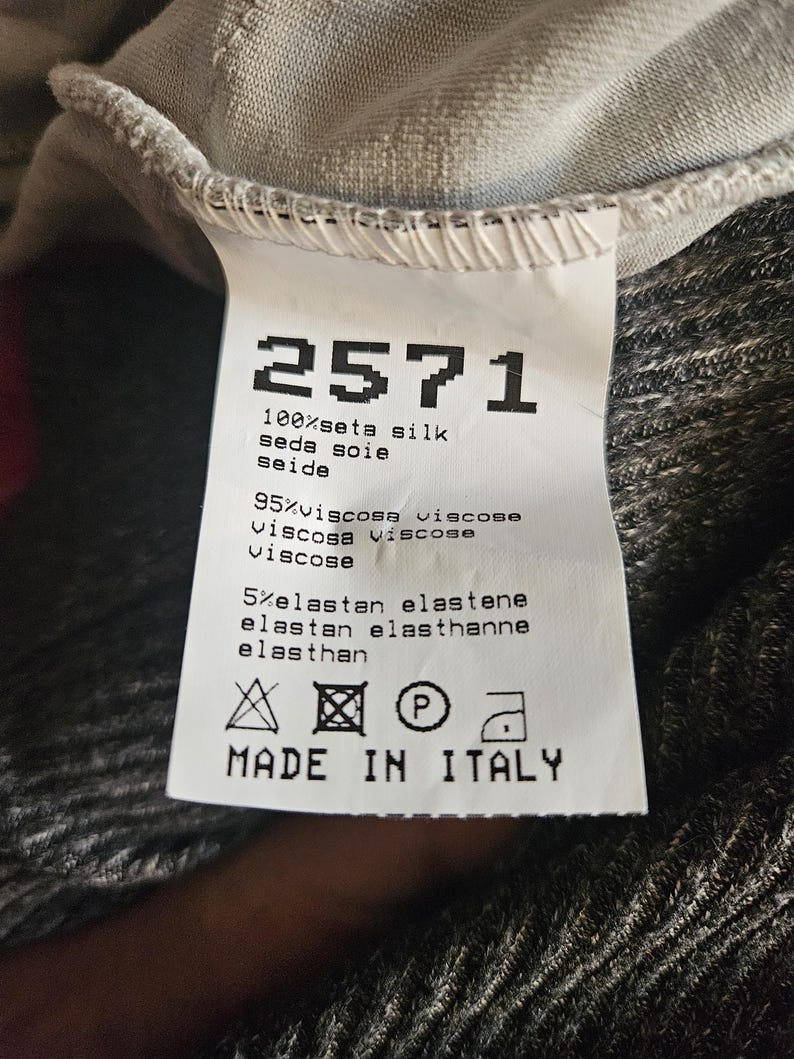 May include: A white label with the number "2571" printed in black, along with fabric composition details: 100% silk, 95% viscose, and 5% elastane. The label also includes care symbols and the text "MADE IN ITALY."