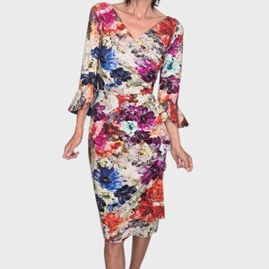 May include: A knee-length dress featuring a vibrant floral print in shades of red, blue, purple, and white. The garment has a V-neckline, three-quarter length sleeves with flared cuffs, and a wrap-style skirt with a gathered side detail.