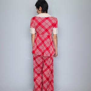 A person wearing a red and white checkered outfit stands facing away from the camera.