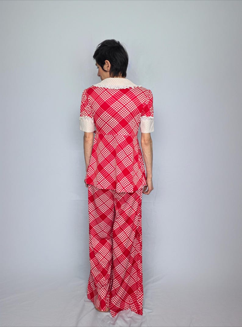 A person wearing a red and white checkered outfit stands facing away from the camera.