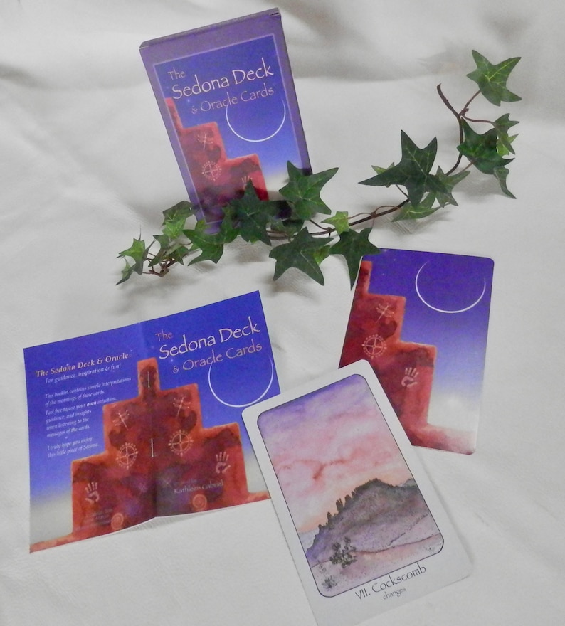 May include: A set of oracle cards with a purple and blue background. The cards feature a red rock formation with symbols and the text "The Sedona Deck & Oracle Cards".