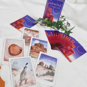 May include: A set of oracle cards with purple and red backgrounds. The cards feature images of landscapes and animals. The cards are titled "The Sedona Deck Oracle Cards".