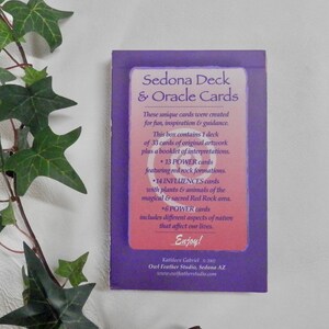 May include: Purple and pink box with the text "Sedona Deck & Oracle Cards". The box contains 33 cards of original artwork, plus a booklet of interpretations. The cards feature red rock formations, plants and animals of the Sedona area, and different aspects of nature.