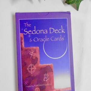 May include: The Sedona Deck & Oracle Cards created by Kathleen Gabriel. The box features a purple background with a red rock formation and a crescent moon in the sky.