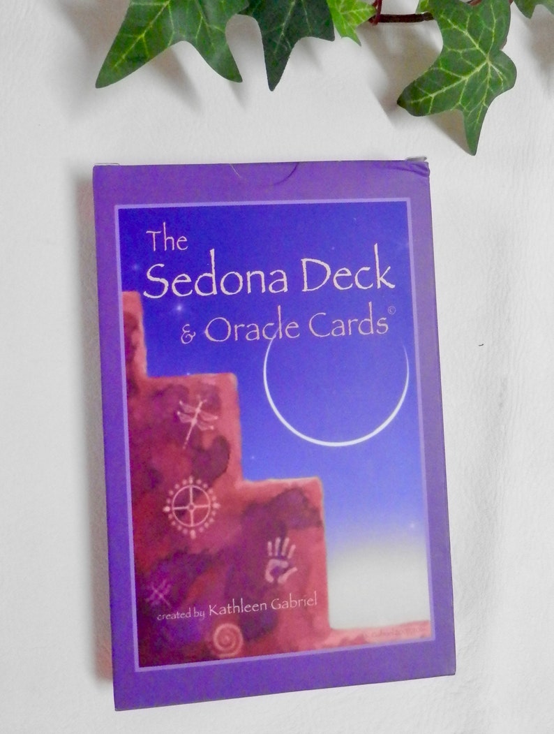 May include: The Sedona Deck & Oracle Cards created by Kathleen Gabriel. The box features a purple background with a red rock formation and a crescent moon in the sky.