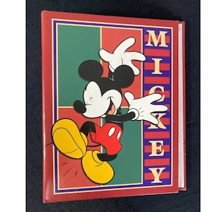 May include: A red, green, and yellow photo album with a cartoon image of Mickey Mouse on the front. The album has the word "MICKEY" printed vertically on the right side.