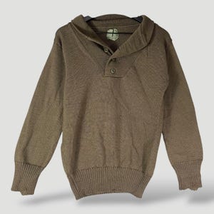 Peut inclure: Un pull marron à manches longues avec un col châle et trois boutons. Le pull a des poignets et un ourlet côtelés. Le col est replié et le pull est suspendu à un cintre noir.