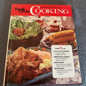 May include: A cookbook titled "Family Circle Illustrated Library of Cooking" with a red banner. The cover features images of various dishes, including fried chicken, corn on the cob, and desserts. A white sticker lists the contents.