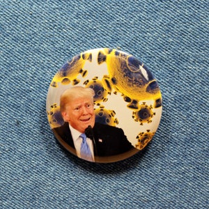 Op de afbeelding: Een ronde knop met een witte achtergrond en een gele en blauwe afbeelding van een persoon met een microfoon voor een achtergrond van gele en blauwe viruscellen.
