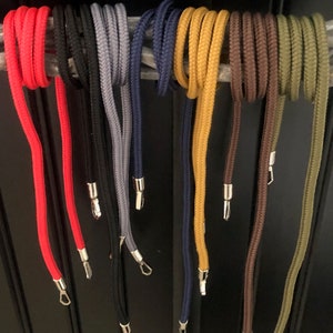 Könnte beinhalten: Sortiment an bunten Schnüren mit silbernen Metallspitzen. Die Schnüre sind rot, schwarz, grau, blau, gelb, braun und grün.