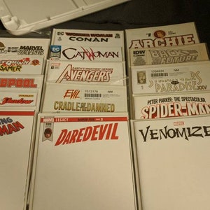 Puede incluir: Una pila de 14 portadas de cómics en blanco con varios títulos, incluyendo "The Amazing Spider-Man", "Daredevil", "Venomized", "Avengers", "Catwoman", "Conan", "Harley Quinn", "Deadpool", "Evil Cradle of the Damned", "Back to the Future", "Paradise X", "Spider-Man" y "Archie".