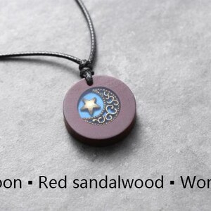 May include: A necklace with a dark red sandalwood pendant featuring a crescent moon and a gold star design.