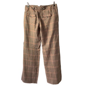 Puede incluir: Pantalones a cuadros marrones con dise&ntilde;o de pierna recta. Los pantalones tienen dos bolsillos traseros con cierre de bot&oacute;n y botones decorativos en la cintura. El patr&oacute;n de cuadros incluye un color rosa claro.
