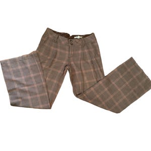 Puede incluir: Pantalones a cuadros marrones con dise&ntilde;o de pierna ancha. Los pantalones presentan un patr&oacute;n de cuadros cl&aacute;sico en tonos marrones y rosas. Los pantalones tienen cierre de bot&oacute;n y cremallera y bolsillos. Los pantalones est&aacute;n hechos de un material suave y c&oacute;modo.