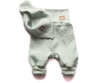May include: A light green baby onesie with a matching light green bib. Both have a small heart-shaped tag with a brown heart cutout.
