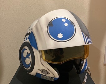 May include: A white and blue pilot helmet with a gold visor and a blue and white star insignia. The helmet has a black and white crescent moon design on the side.