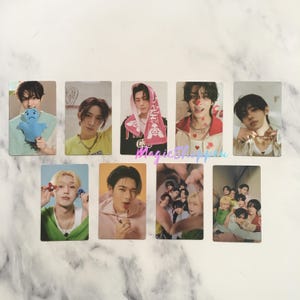 Puede incluir: Un conjunto de diez tarjetas fotográficas con diferentes miembros de una banda de chicos K-pop. Las tarjetas están impresas en papel brillante y presentan imágenes coloridas de los miembros de la banda. Las tarjetas son perfectas para los fans de la banda.