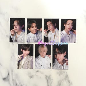 May include: Set of seven rectangular photo cards featuring young men in white jackets and shirts, each with a finger touching their cheek. The cards have a black background and are arranged in two rows.