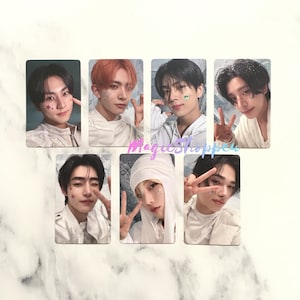 Pode incluir: Sete cartões de fotos com diferentes membros de uma banda de meninos. Cada cartão tem um fundo branco e apresenta um retrato de close-up de um jovem com um penteado e uma expressão diferentes. As fotos estão dispostas em duas filas de três e uma fila de uma.