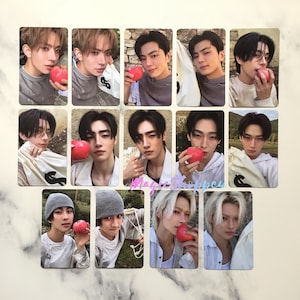 May include: A collection of rectangular photo cards featuring young men holding red apples. The cards have a light beige border and a soft focus background. The men are wearing various casual outfits.