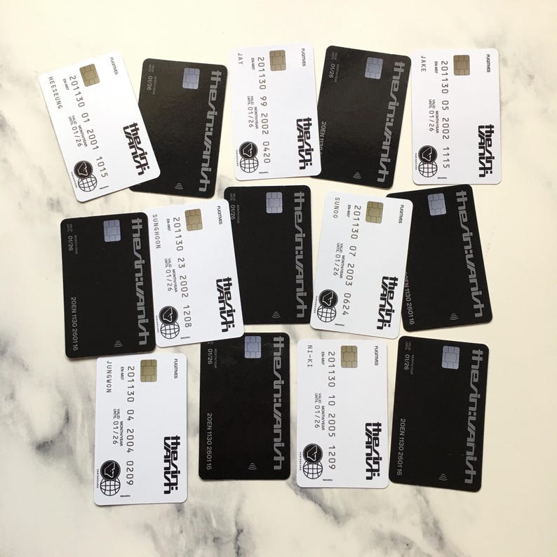 May include: An assortment of black and white rectangular cards with rounded corners. Each card features the text "the:in:vanish" in a stylized font, along with other printed details. Some cards have names and dates. The cards are arranged on a light-colored surface.