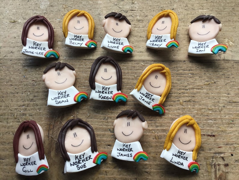 Op de afbeelding: Een verzameling van 10 kleurrijke sleutelwerknemer-badges. Elke badge heeft een cartoon gezicht met een regenboog en de tekst "Sleutelwerknemer" en een naam. De namen zijn Jamie-Lee, Becky, Luke, Tracy, Ian, Sean, Karen, Jane, Gill, Sue, James en Linda.