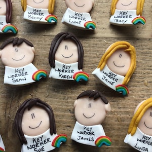 Op de afbeelding: Een verzameling kleurrijke sleutelwerknemer-badges met regenboogaccenten. Elke badge heeft een cartoongezicht en de tekst "Sleutelwerknemer" gevolgd door een naam. De namen zijn Jamie-Lee, Becky, Luke, Tracy, Ian, Sean, Karen, Jane, Sue, James en Linda.