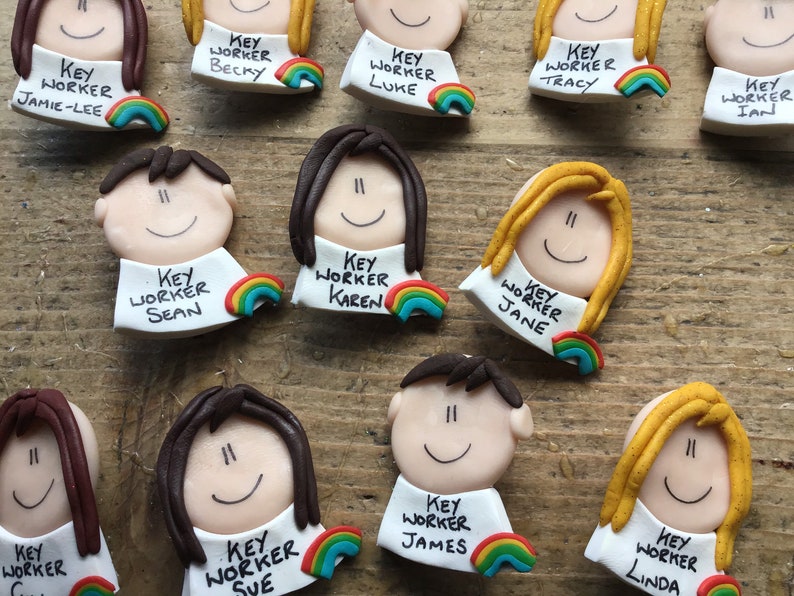 Op de afbeelding: Een verzameling kleurrijke sleutelwerknemer-badges met regenboogaccenten. Elke badge heeft een cartoongezicht en de tekst "Sleutelwerknemer" gevolgd door een naam. De namen zijn Jamie-Lee, Becky, Luke, Tracy, Ian, Sean, Karen, Jane, Sue, James en Linda.