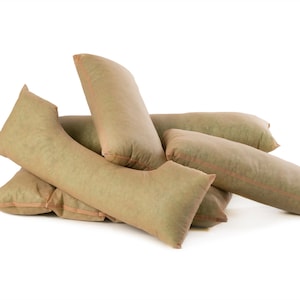Puede incluir: Un conjunto de cinco almohadas de color beige hechas de una tela texturizada. Las almohadas están dispuestas en una pila sobre un fondo blanco.