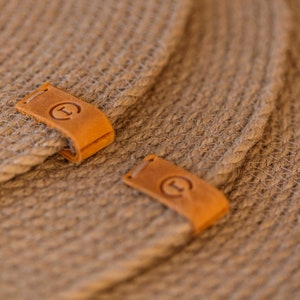 May include: Two brown woven placemats with leather labels that say "T" in a circle.