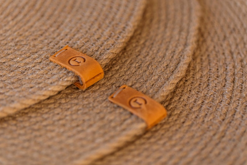 May include: Two brown woven placemats with leather labels that say "T" in a circle.