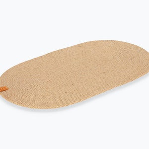 May include: An oval rug made from natural woven rope with a brown leather tag. The rug is beige and has a subtle texture.