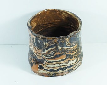 May include: A brown, black, and white ceramic planter with a wavy, abstract pattern. The planter is made of earthenware and has a wide, round opening.