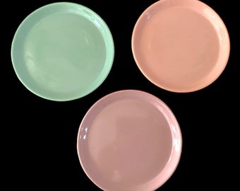 Könnte beinhalten: Drei runde Keramikteller, einer grün, einer rosa und einer hellrosa.