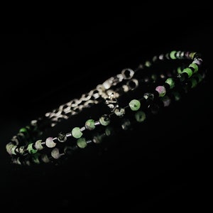 Peut inclure: Un bracelet délicat avec des perles vertes et noires alternées. Le bracelet est composé de petites perles rondes enfilées sur une chaîne en argent.