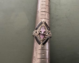 Vacated Amathist and jet ring with tiny faceted stones around it.