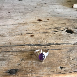 May include: A silver ring with a purple amethyst gemstone set in a pointed, leaf-shaped design.