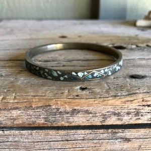 May include: A silver bangle bracelet with a decorative pattern of blue and white enamel.