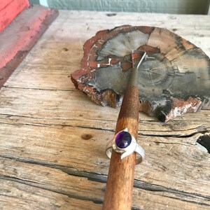 May include: A silver ring with a purple gemstone set in a crescent moon design.