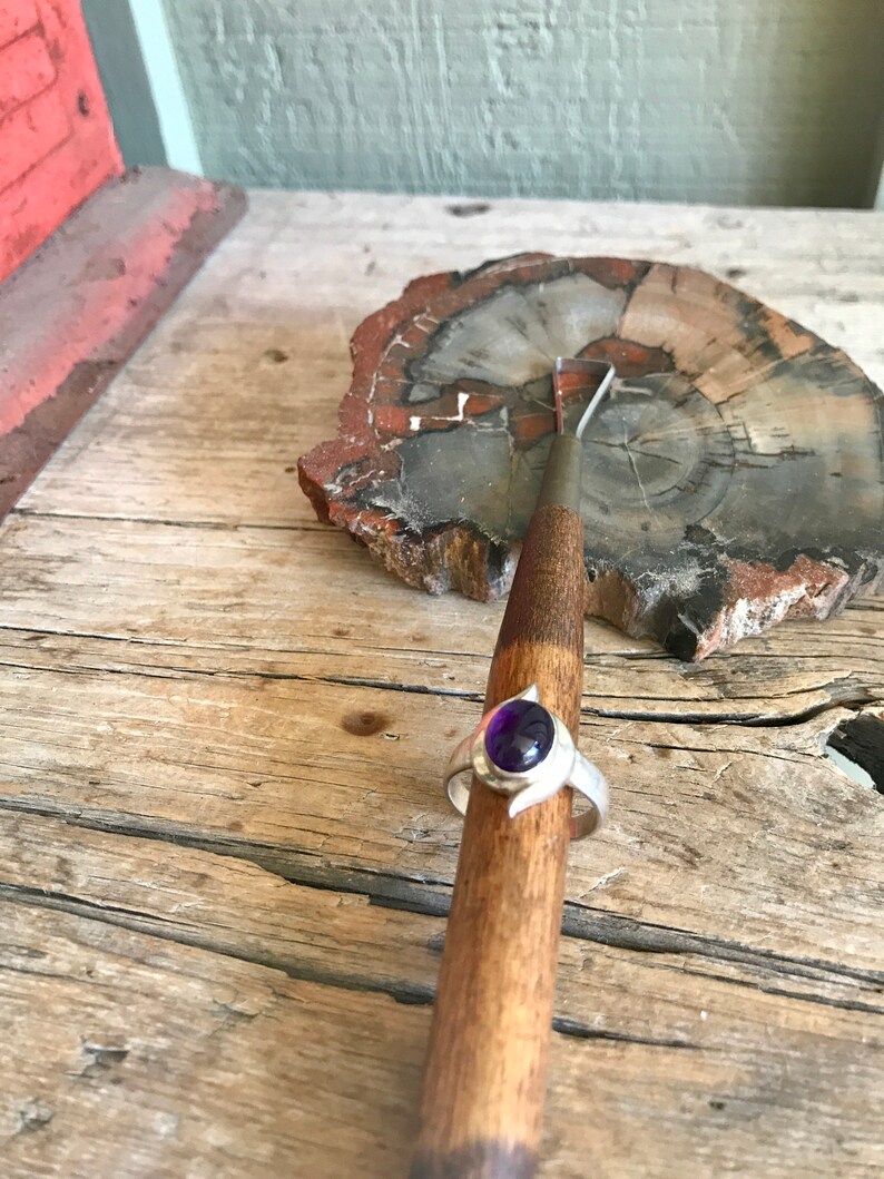 May include: A silver ring with a purple gemstone set in a crescent moon design.