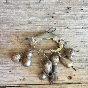 May include: A silver charm bracelet with a variety of charms, including bells, gourds, and a small bird. The bracelet is made of metal and has a clasp closure.